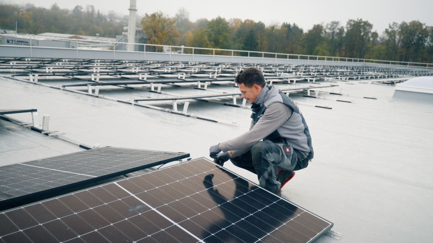 Monteur bei der Installation einer Photovoltaikanlage auf einem Flachdach